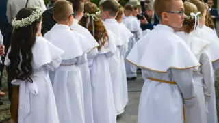 Dzieci w białych strojach komunijnych, dziewczynka z wiankiem na głowie. Piękne życzenia na komunie dla wszystkich.
