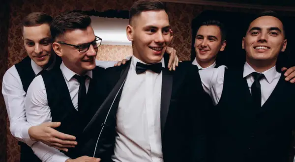 Uśmiechnięci panowie w garniturach, przygotowani na wieczór kawalerski.