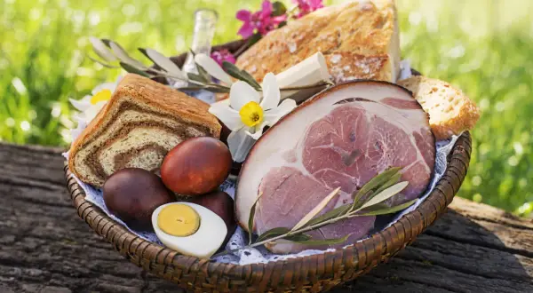Koszyk wielkanocny z szynką, jajkami i chlebem. Czy w Wielką Sobotę można jeść mięso? Tradycja mówi, że nie, ale to zależy od regionu.