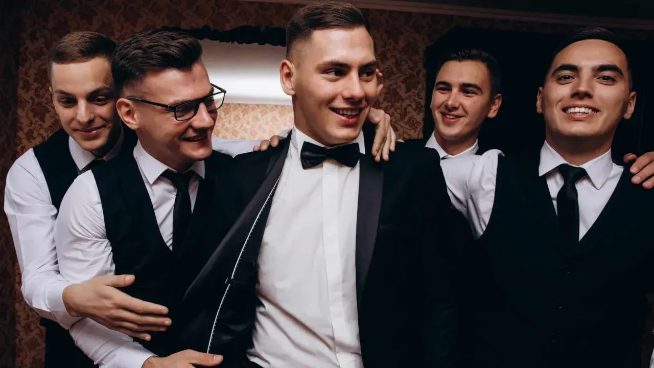 Uśmiechnięci panowie w garniturach, przygotowani na wieczór kawalerski.